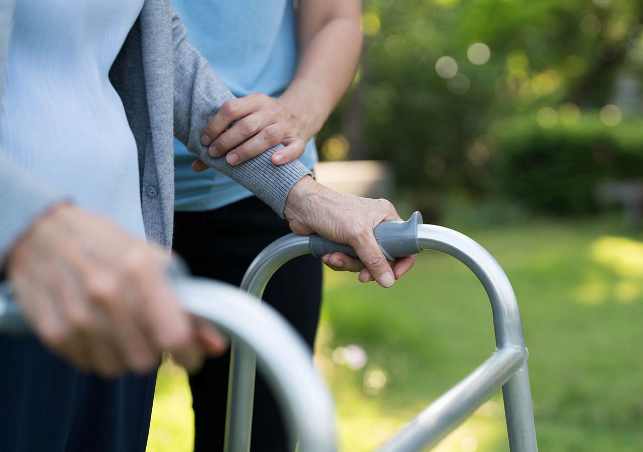 Hospice care worker helping patient with walker